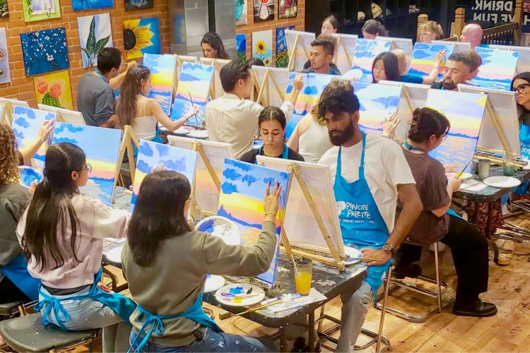 People in blue aprons painting in a class