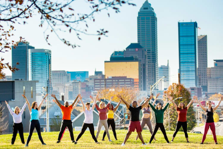 People dancing in a park next to the Indianapolis skyline