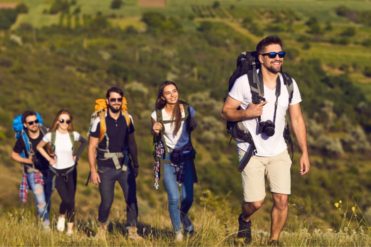 Five people hiking through a grassy area