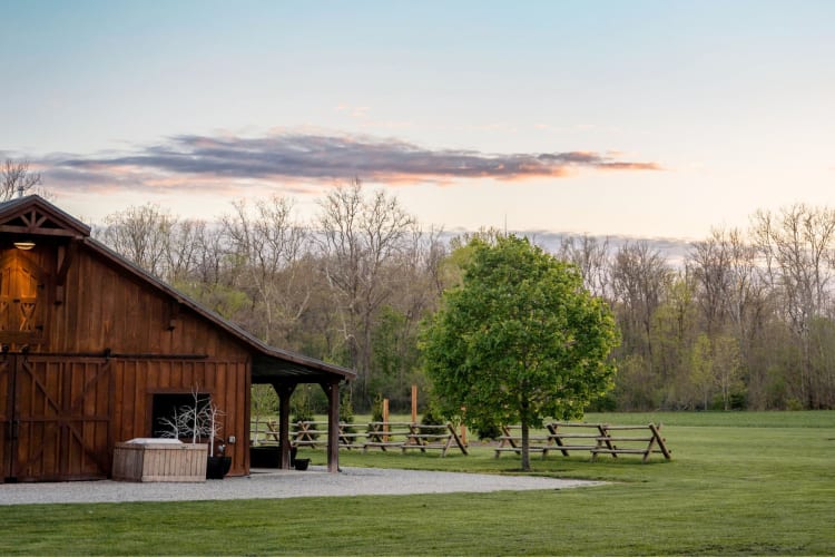 A barn at sunset next to grass and trees