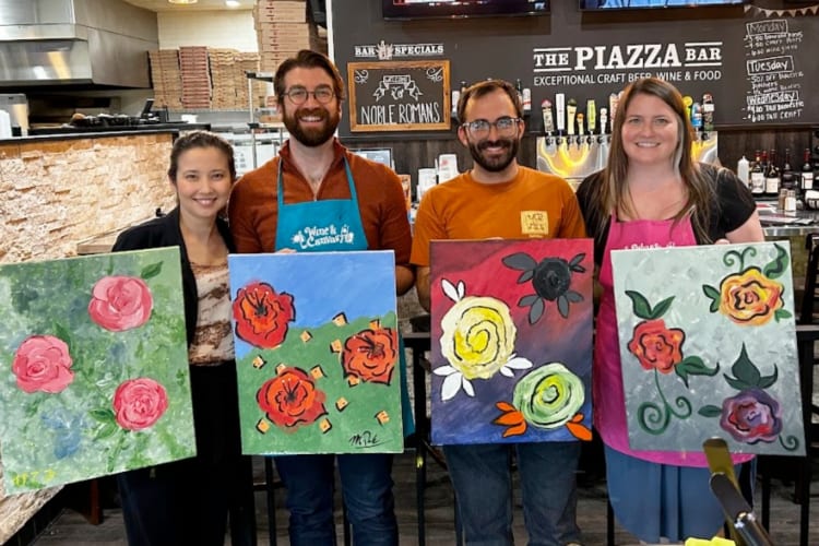 People holding paintings created in a paint and sip class
