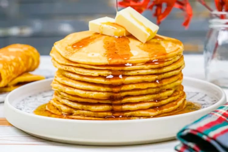 A stack of pancakes topped with syrup and butter