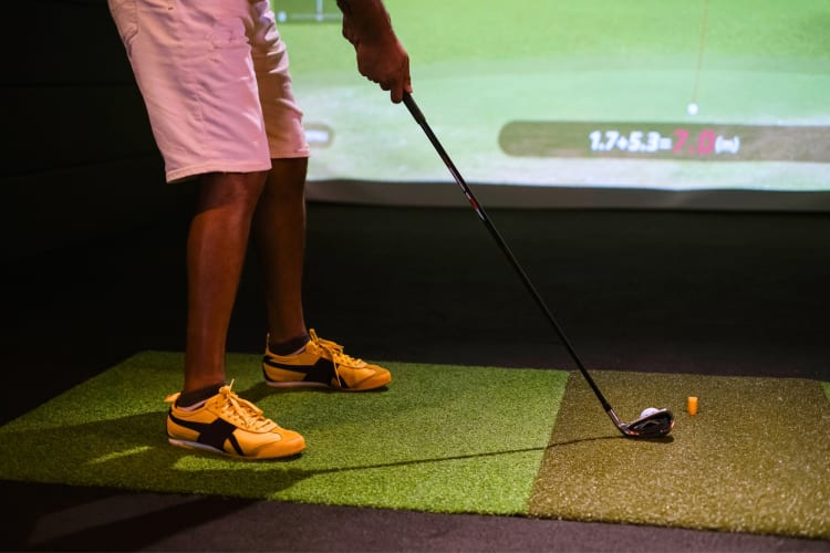 A person hitting a golf ball at an indoor golf course