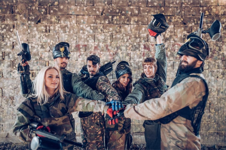 A team of people in paintball gear in front of a wall