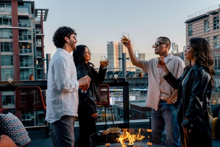 A group of people toast with drinks on rooftop bar in San Diego's Gaslamp Quarter