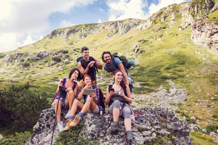 Five people in hiking gear sitting on rocks surrounded by hills