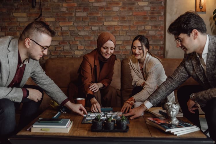 four people at a table playing a board game together