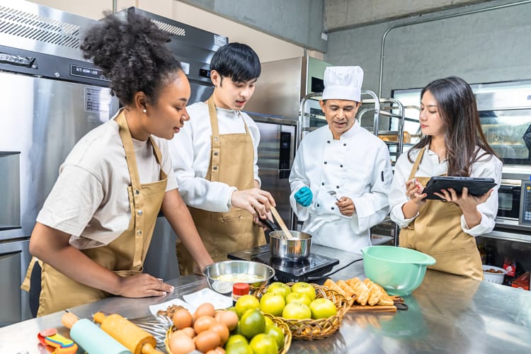 Three teens taking a cooking class with a chef, as a teen birthday party idea