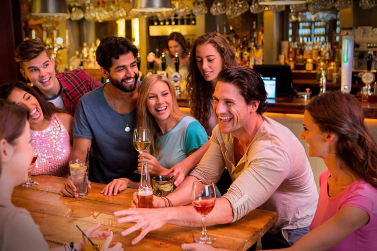 Eight friends laughing and enjoying a drink together at a bar