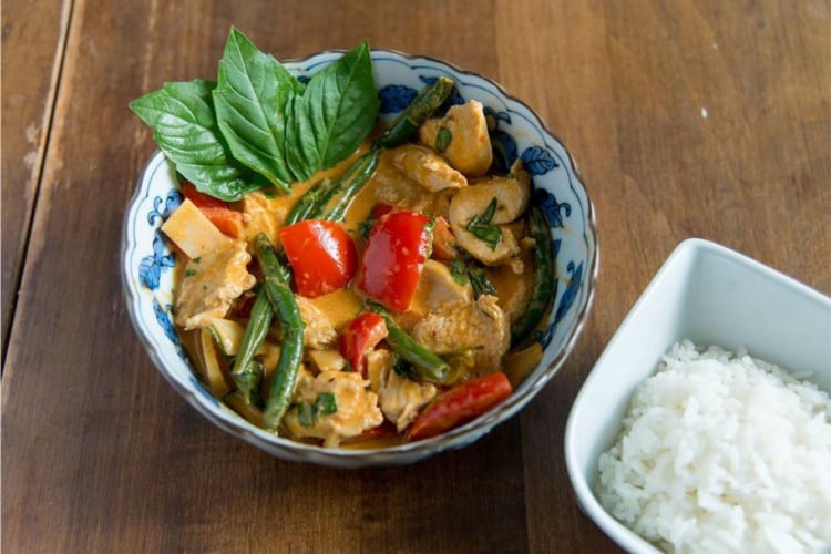 A bowl curry with vegetables and Thai basil on top