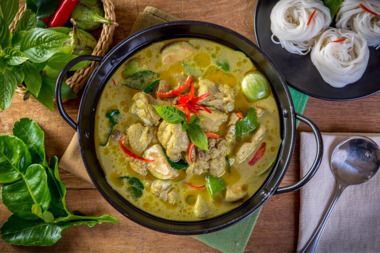 A bowl of green curry with Thai basil on top