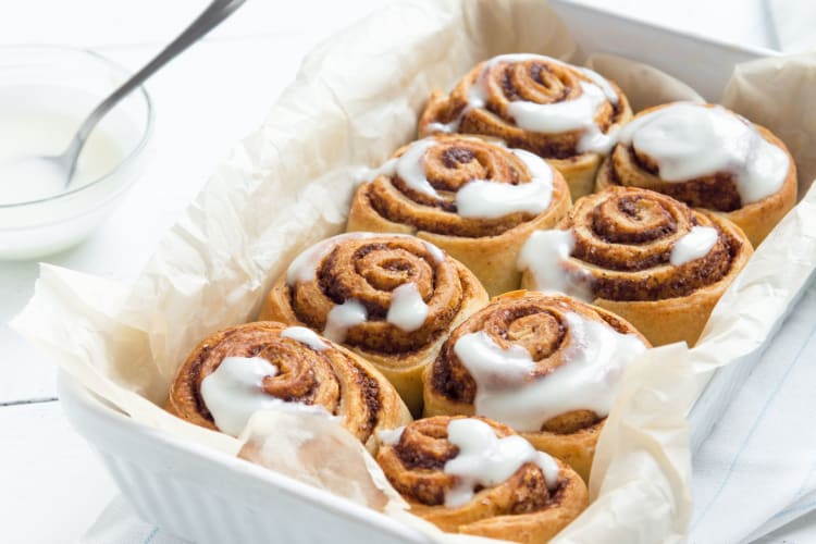 A white dish with iced cinnamon rolls packed inside.