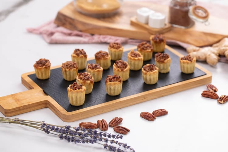 A serving board with lots of mini pecan pies.
