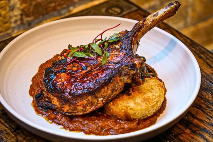 Piece of meat with a baked potato and sauce from Thattu, an Indian restaurant in Chicago