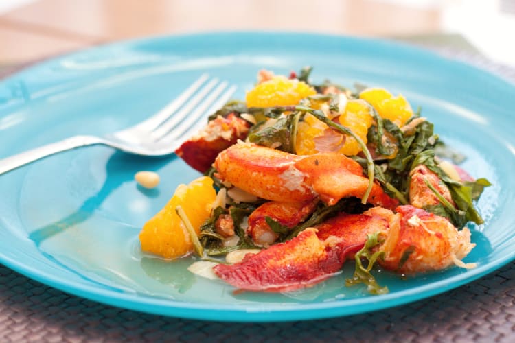 Lobster dish on a blue plate next to a fork