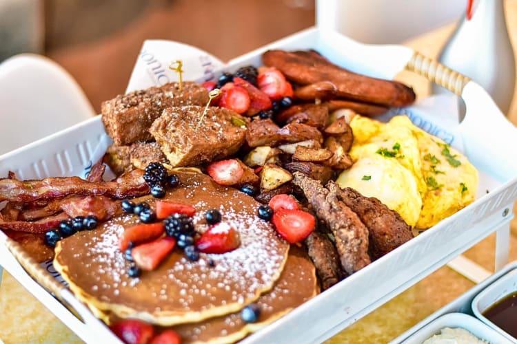 Breakfast meal with egg, French toast, pancakes, bacon and fruit from The Monica