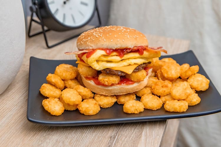 Burger from the Carl's Jr. breakfast menu on top of hash rounds© on a plate