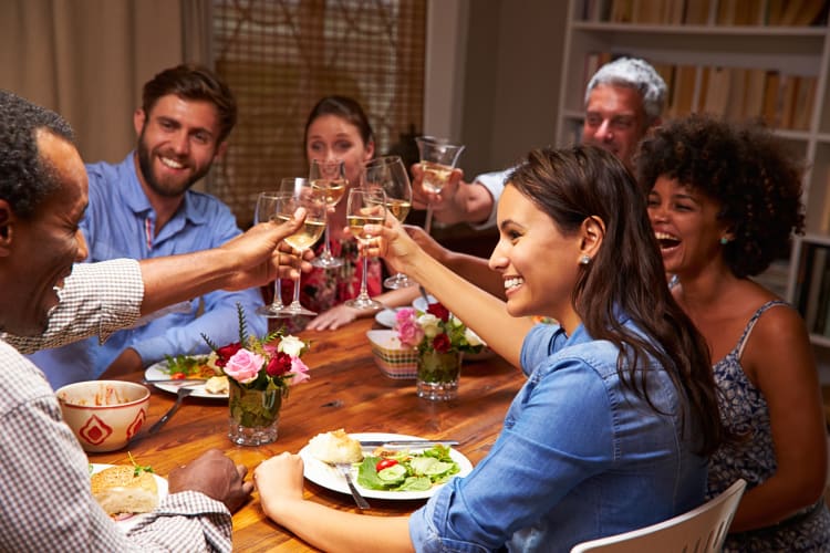 Six friends toasting at a dinner party