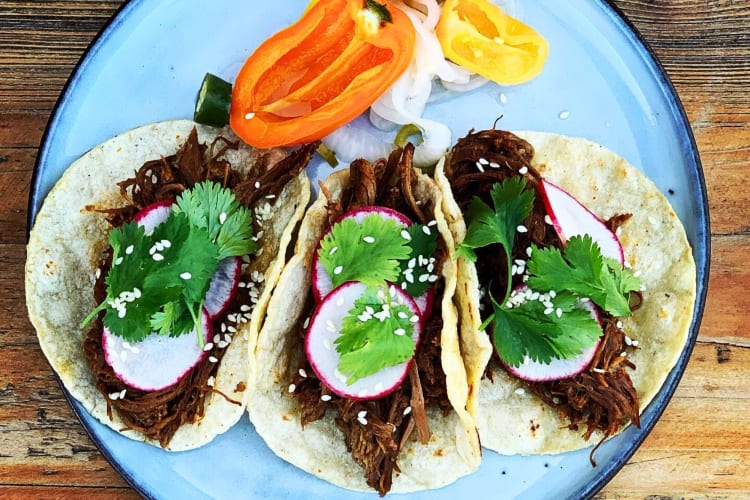 Three meat tostadas with vegetables on the side from Tinie’s