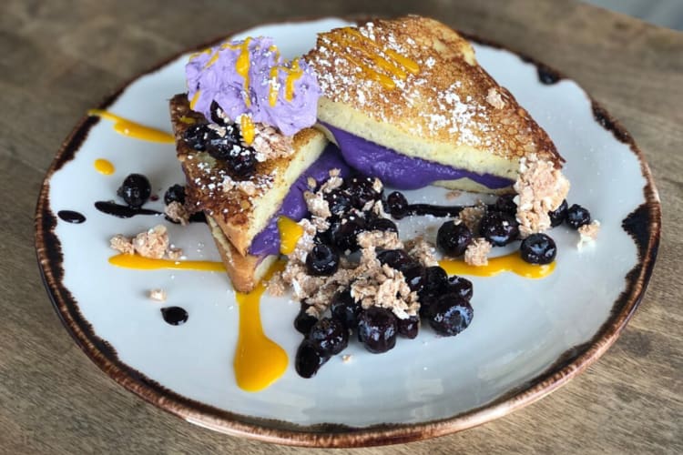 Breakfast dish stack with blueberries and purple and orange sauce on top from Orange County restaurant Toast Kitchen and Bakery