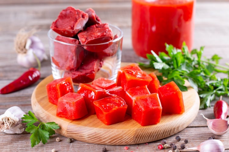 Frozen tomato paste cubes on a wooden board