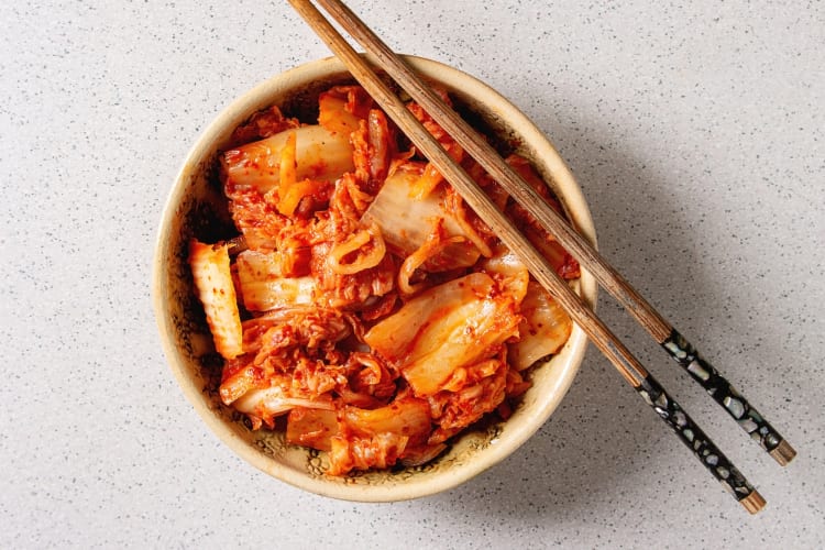 A bowl of probiotic-rich kimchi with chopsticks resting on it