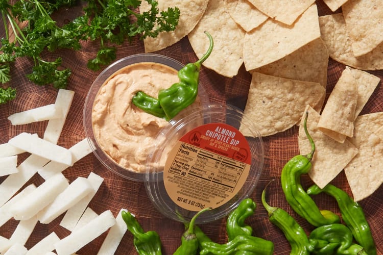 A tub of Almond Chipotle Dip with tortilla chips and raw vegetables