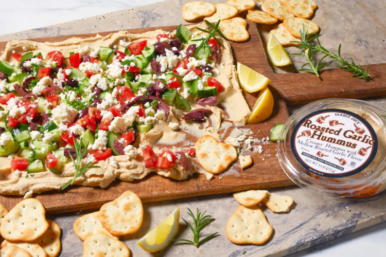 Roasted hummus on a board with olives, feta and cucumbers