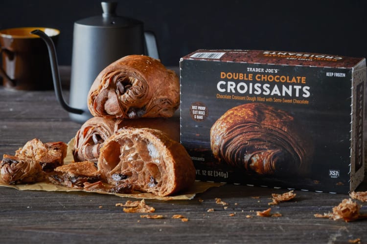 A box of double chocolate croissants next to fresh double chocolate croissants 