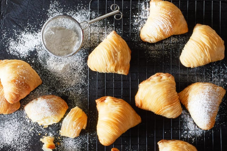 Sfogliatella pastries on sprinkled with powdered sugar on a cooling rack