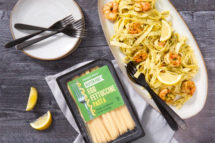 A box of Trader Joe's Gluten-Free Egg Fettuccine Pasta next to a plate of pasta with shrimp