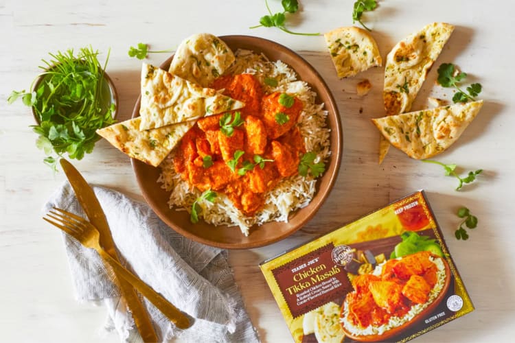A bowl of chicken tikka masala with rice and naan
