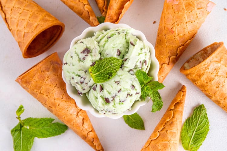 A bowl of mint chip ice cream surrounded by ice cream cones
