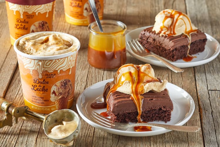 Cake topped with ice cream next to tubs of dulce de leche ice cream