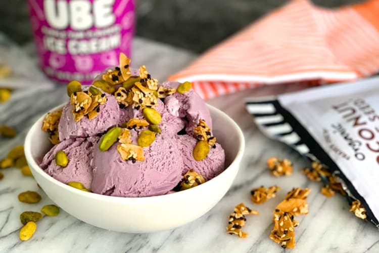 A bowl of purple ube ice cream with granola and pepita sprinkles