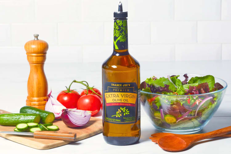 A bottle of Trader Joe's olive oil next to salad ingredients