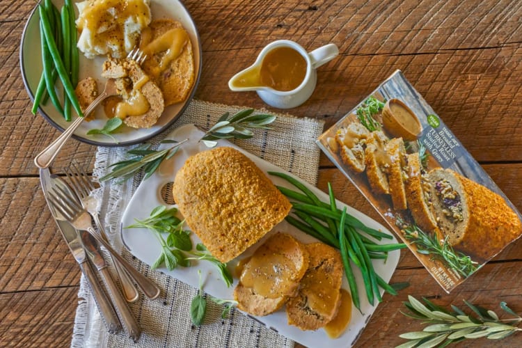 A vegan breaded turkey with gravy, green beans and mashed potatoes
