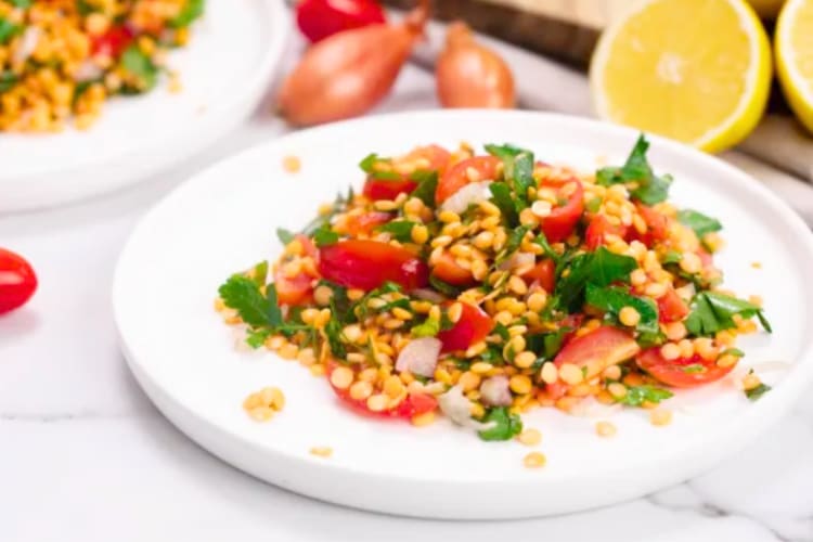 Lentil tabbouleh salad on a plate with fresh lemons behind