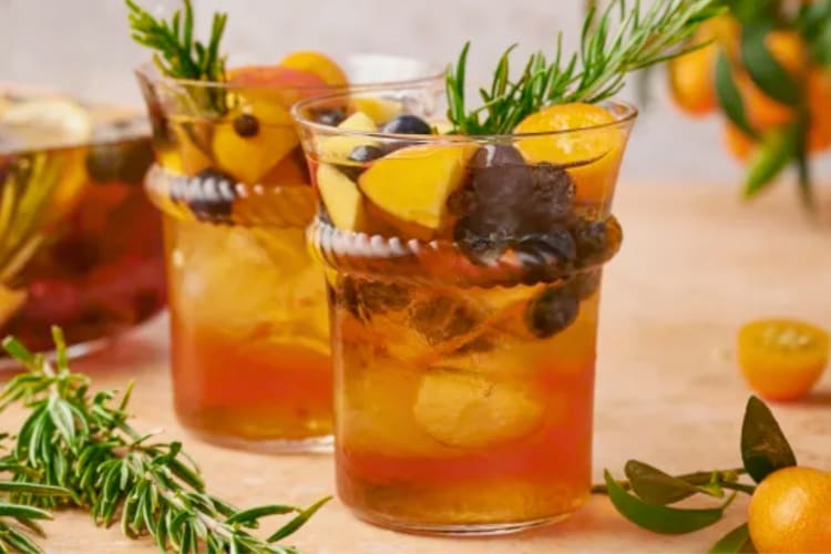 Two glasses of Moscato sangria surrounded by herbs