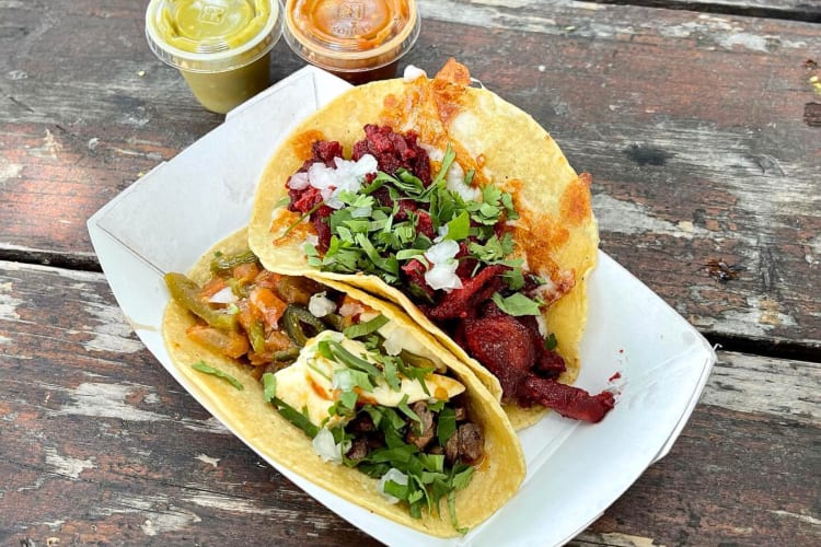 Two tacos and two containers of sauce, from Trompo, a restaurant that sells fast food in Dallas