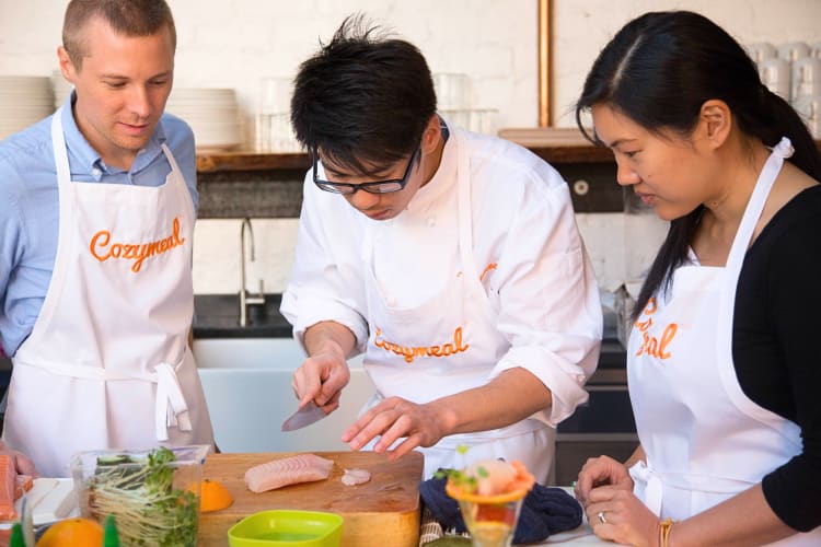 Two people taking a cooking class with a professional chef, booked through Cozymeal