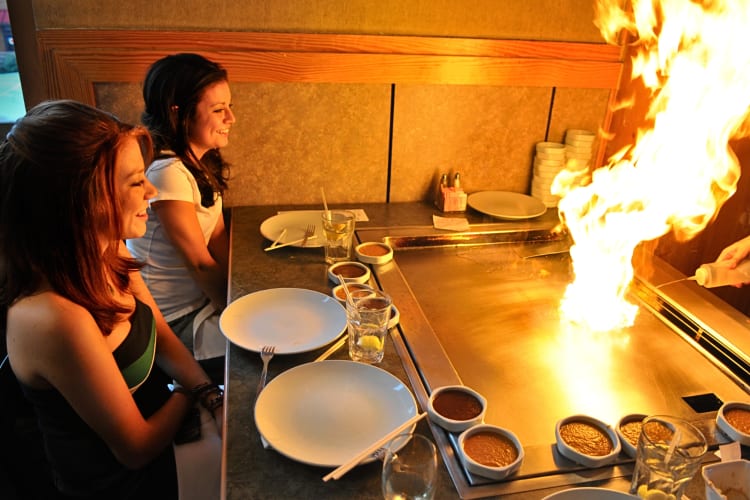 Two ladies looking at a flame made by a hibachi chef