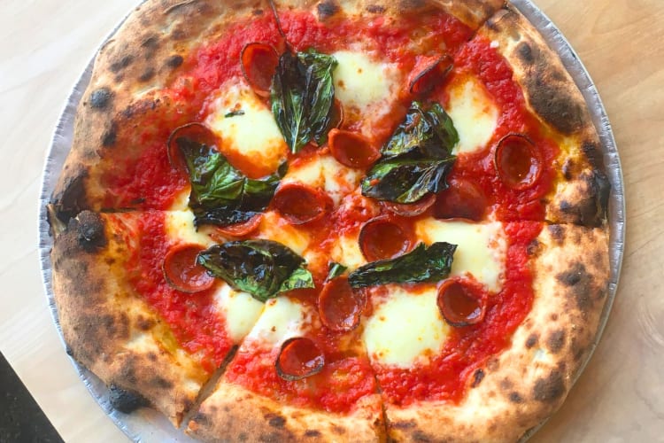 A pizza with mozzarella, basil and pepperoni