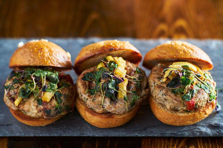 Three turkey burger slides with pineapple and greens on top