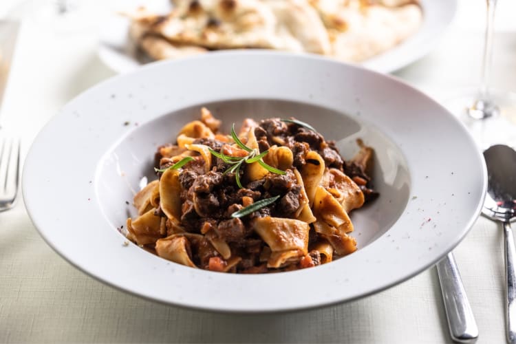 A bowl of pappardelle pasta with a meat sauce