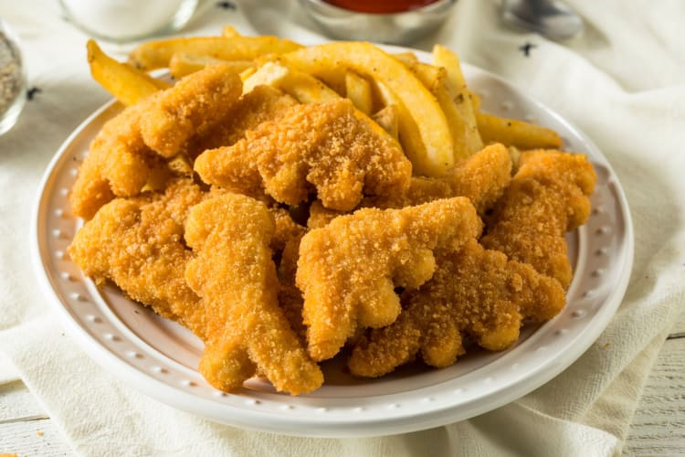 A plate of dinosaur-shaped breaded chicken nuggets