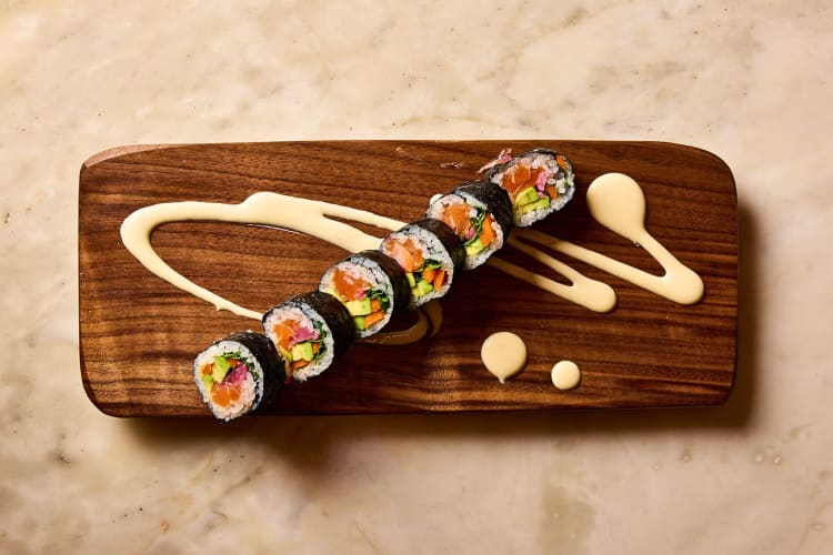 Aerial shot of six pieces of sushi on a wooden board with sauce, from Uchi