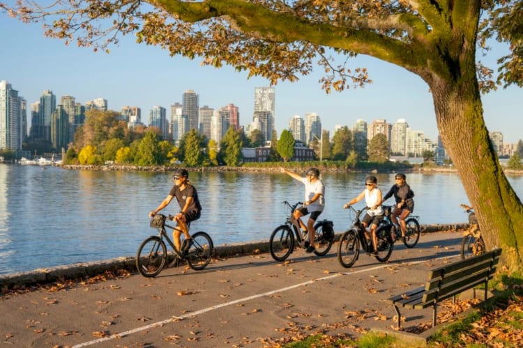 People biking next to water and city buildings
