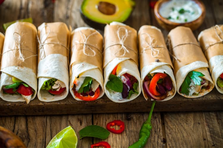 Variety of tortilla wraps in a row, wrapped in paper and tied with string