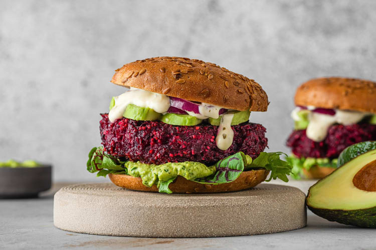 Side-view of a vegan burger with guacamole, mayonnaise and greens